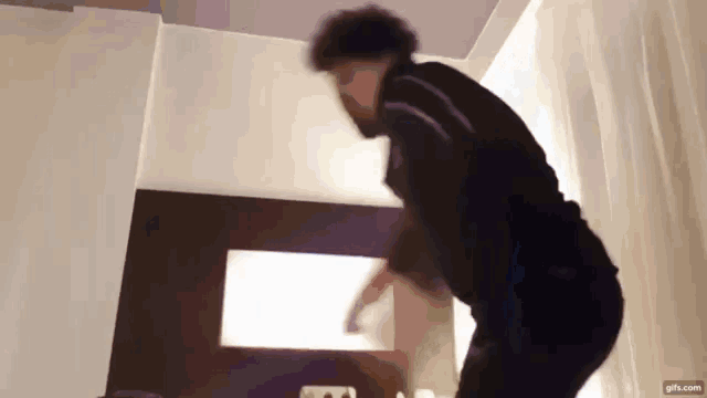 a man in a black shirt is dancing in a room .
