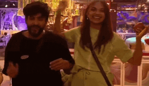 a man and a woman are standing next to each other in a room . the woman is holding an apple in her hand .