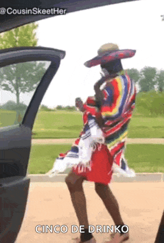 a man wearing a sombrero and a poncho is standing next to a car .