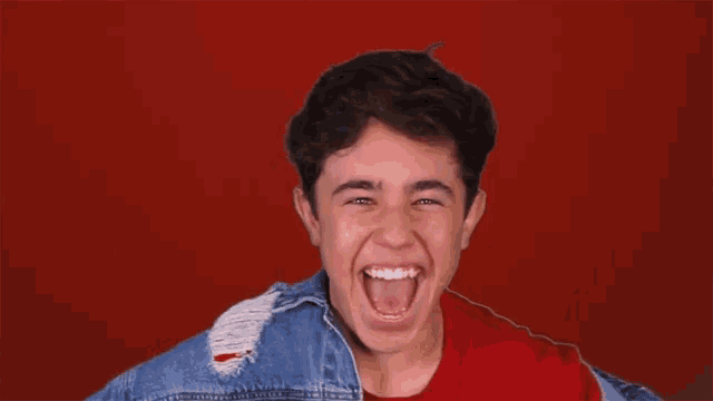 a young boy is smiling in front of a red background with the words que oso in white letters