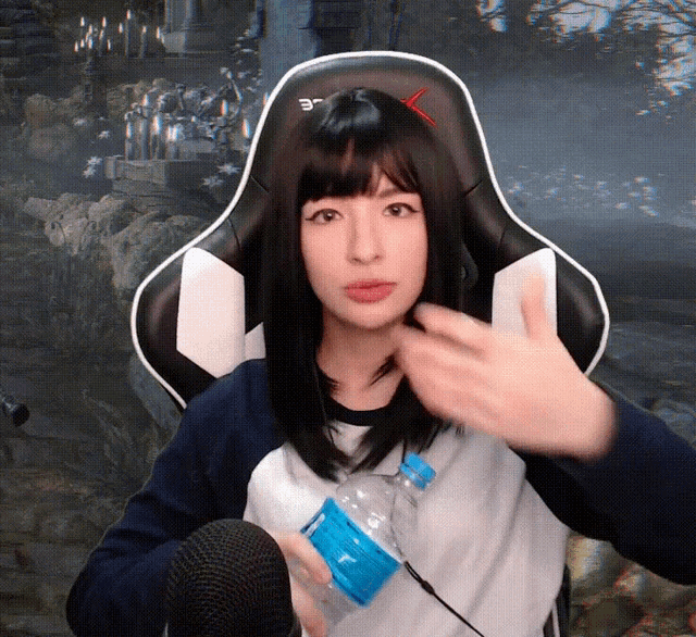 a woman in a gaming chair holds a bottle of water in front of a microphone