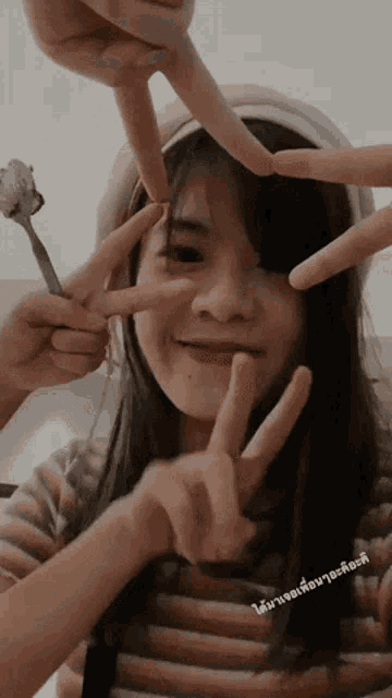 a girl making a peace sign with her fingers in front of her face