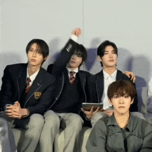 a group of young men in school uniforms are sitting together