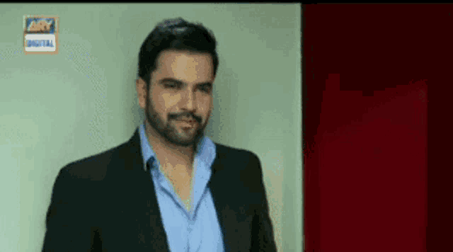 a man in a suit and blue shirt is standing in front of a sign that says ary