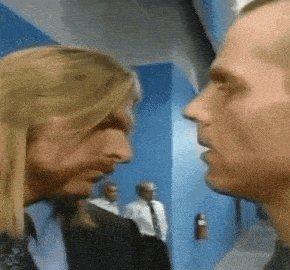 two men are facing each other in a room with a fire extinguisher on the wall