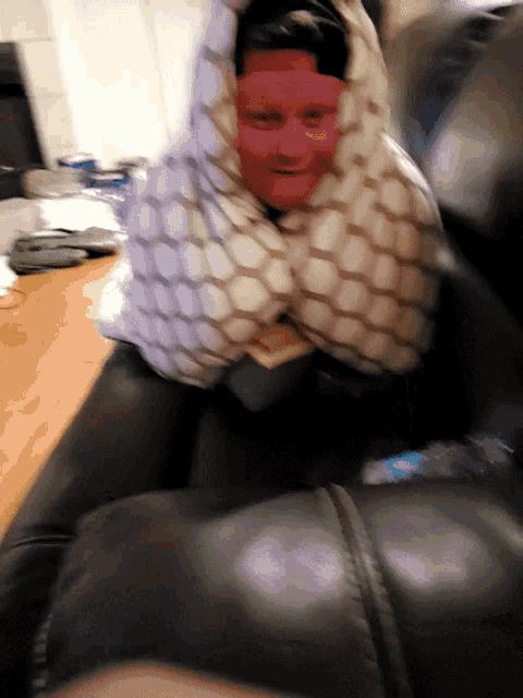 a man sitting on a couch with a pillow on his head