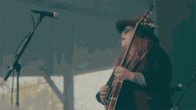 a woman singing into a microphone while holding a guitar