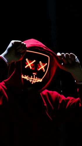 a person in a red hoodie is wearing a neon mask with x 's on it