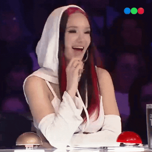 a woman with red hair is laughing while sitting in front of a red button