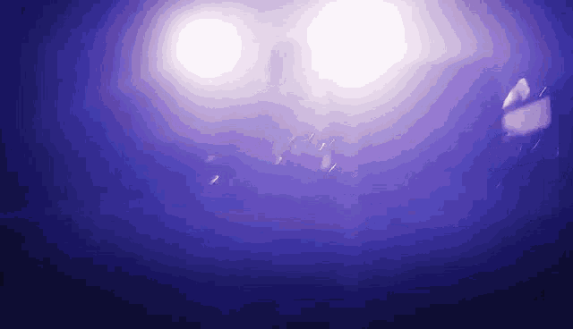 a blurry picture of a person in a dark room with purple lights behind them