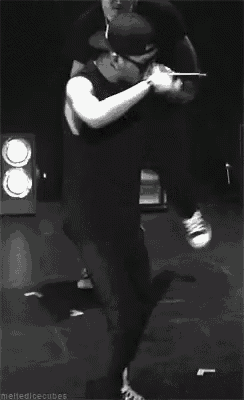 a black and white photo of a man holding a microphone while dancing on a stage .