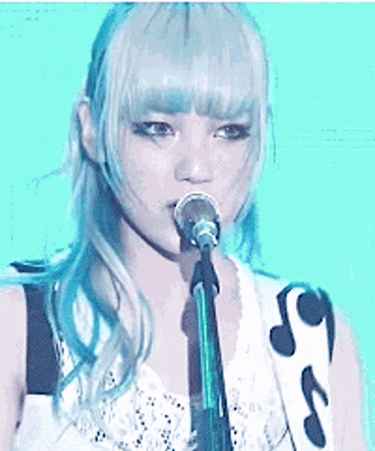 a woman singing into a microphone with a guitar strap that has music notes on it