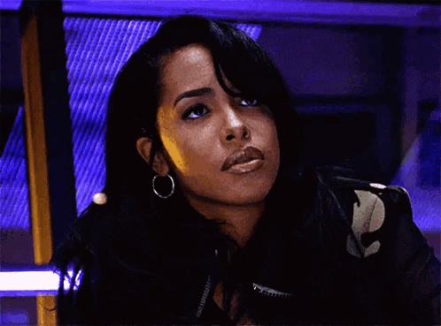 a close up of a woman wearing hoop earrings and a black jacket looking at the camera .