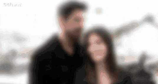 a blurry picture of a man and a woman standing next to each other