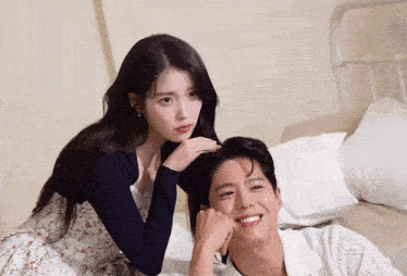 a man and a woman are sitting next to each other on a bed and smiling