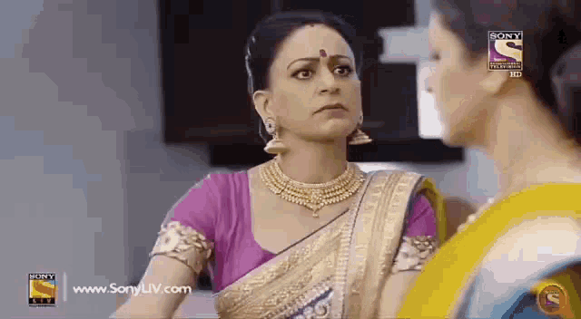 two women are standing next to each other in a room and talking .