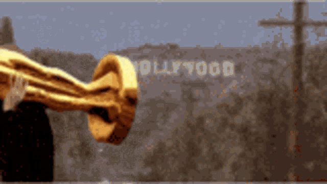 a person holding a gold trophy in front of a sign that says hollywood