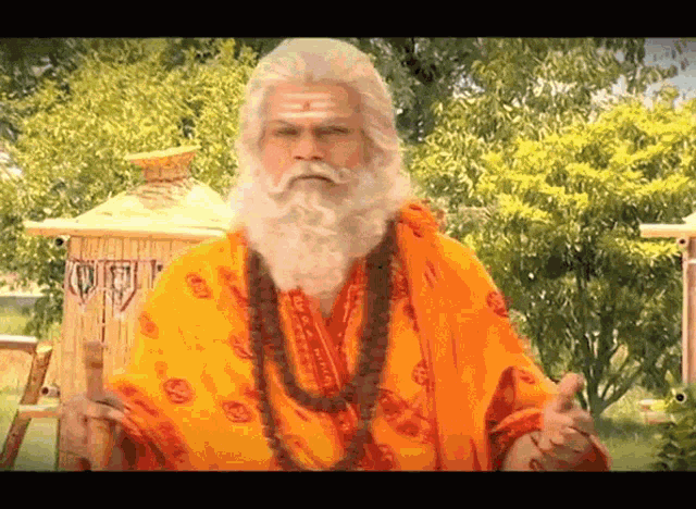 a man with a long beard and a yellow robe is standing in front of trees
