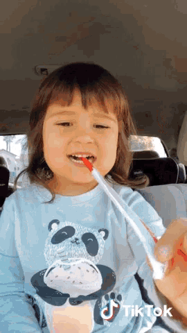 a little girl is brushing her teeth in a car with a tiktok watermark