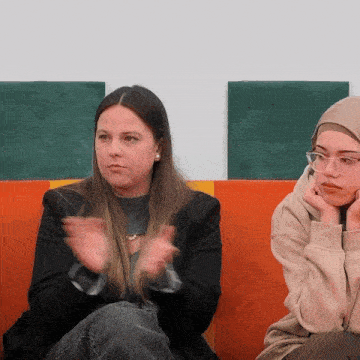 a woman wearing glasses sits next to another woman