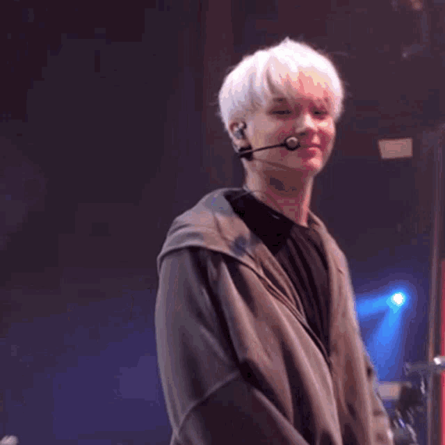 a man wearing a grey hoodie is dancing on stage