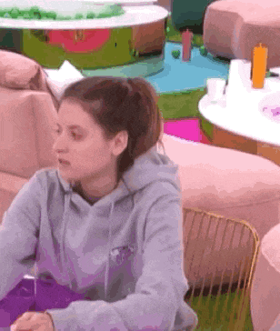 a woman wearing a grey hoodie is sitting at a table