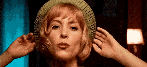 a woman wearing a green hat is making a face .