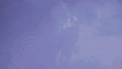a woman singing into a microphone in front of a purple background