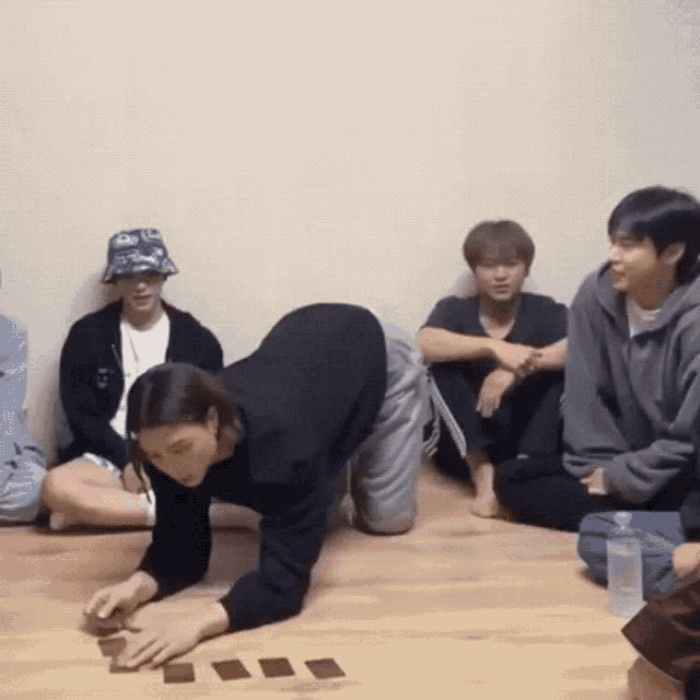 a group of people are sitting on the floor playing a game with cards .
