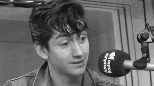 a young man is sitting in front of a microphone in a black and white photo .