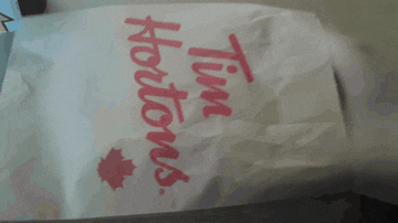 a person is holding a bag of tim hortons
