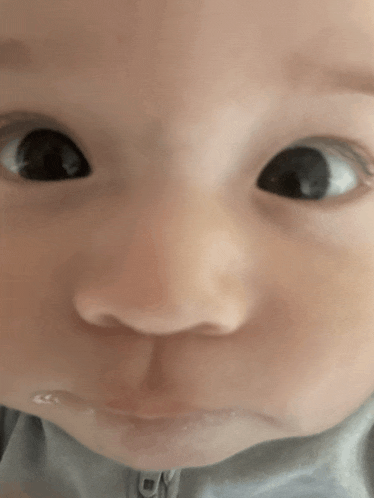 a close up of a baby 's face with a gray shirt that says cy