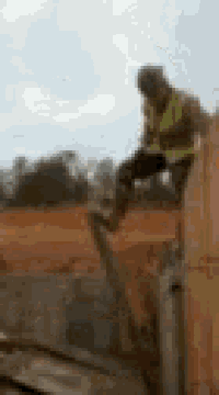 a blurry picture of a construction worker sitting on top of a concrete wall .