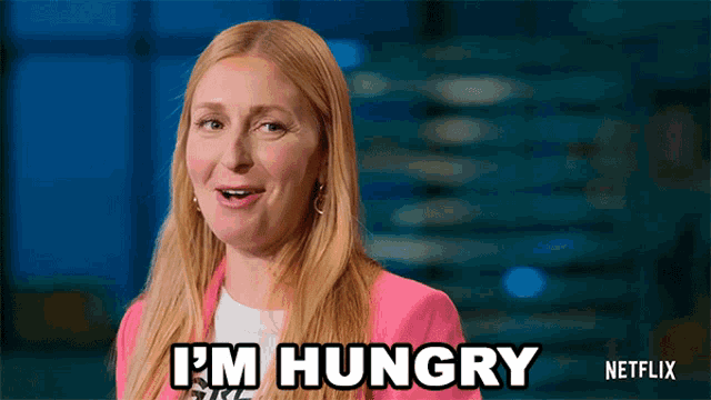 a woman says i 'm hungry in a pink jacket