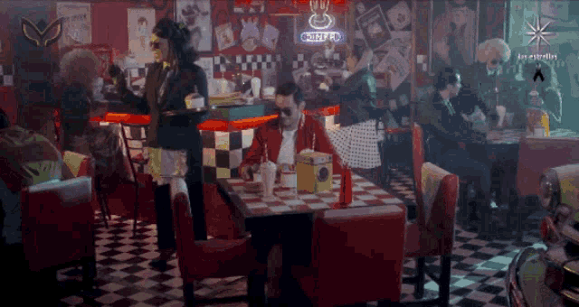 a man sits at a table in a diner with a sign that says chipotle in the background