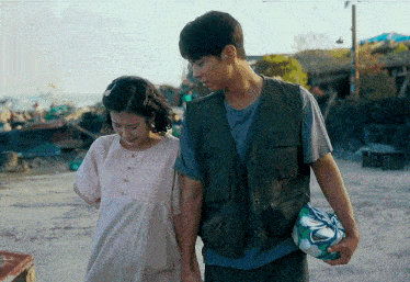 a man and a woman are holding hands while walking on the beach