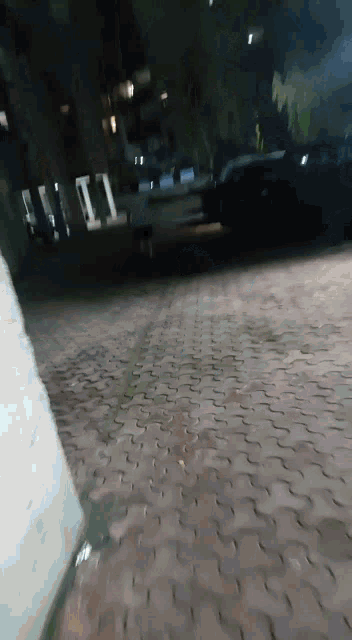 a brick sidewalk with a few cars parked on it at night