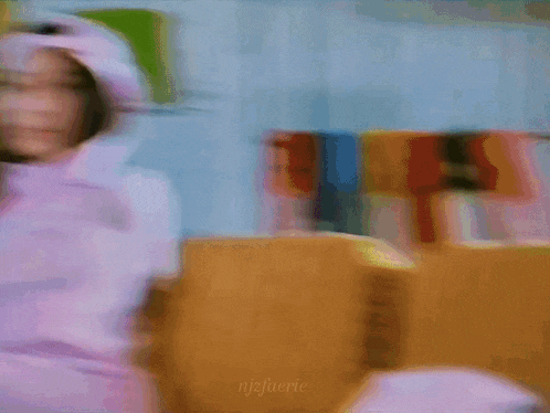 a blurry picture of a woman in a pink hat and sweater .