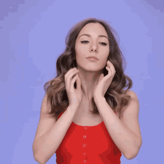 a woman in a red tank top covering her ears