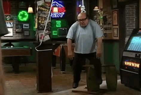 a man is standing on a barrel in a bar with a bud light sign in the background .