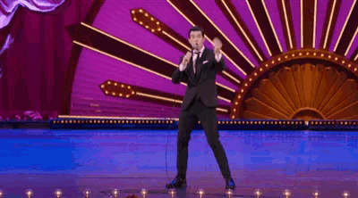 a man is dancing on a stage in front of a crowd of people in an auditorium .