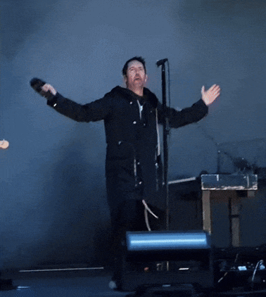 a man is singing into a microphone with his arms outstretched