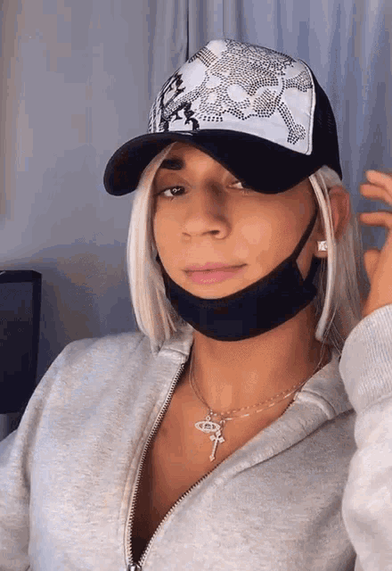a woman wearing a hat and a mask has a key necklace on her neck
