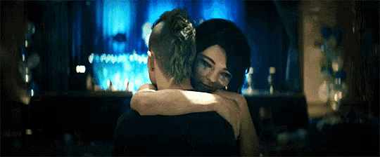 a man and a woman hugging in front of a blue curtain