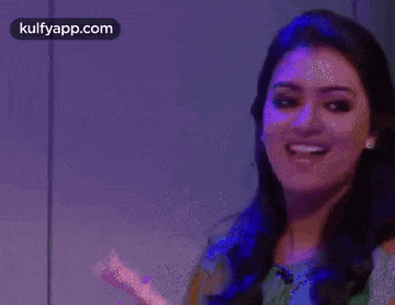 a woman is smiling in front of a purple background .