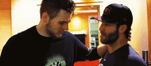 two men are standing next to each other in a room and looking at each other .