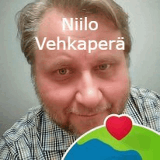 a man with the name niilo vehkapera on his forehead is holding a heart shaped sticker .