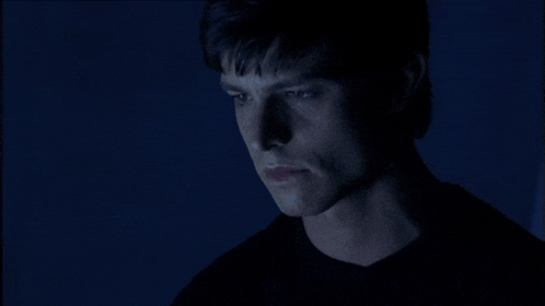 a close up of a man 's face in the dark with blue eyes
