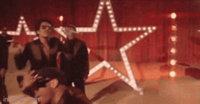 a group of men are dancing on a stage with a star in the background