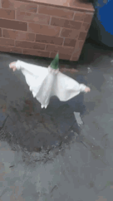 a bird scarecrow is sitting on a brick wall next to a bucket